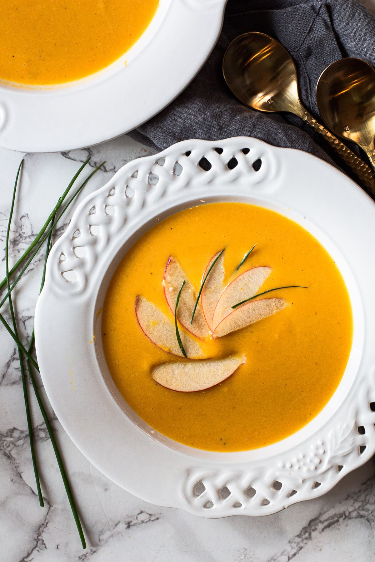Butternut squash and apple soup garnished with sliced apples and chives