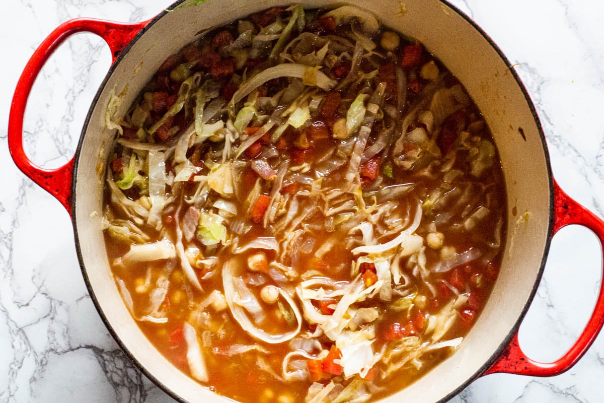 Cabbage, chickpeas and tomatoes in a tomato broth for chorizo soup.