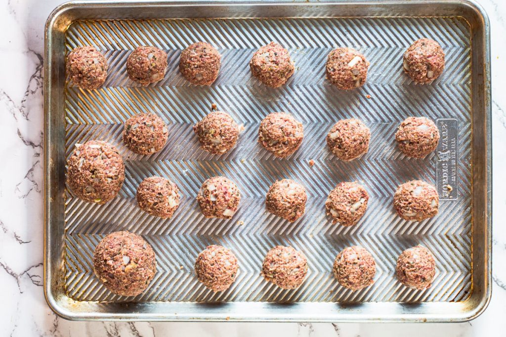 Homemade meatballs on a sheet pan ready to bake.