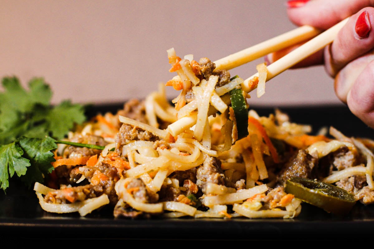 Eating Pad thai noodles with peanut sauce with chop sticks.