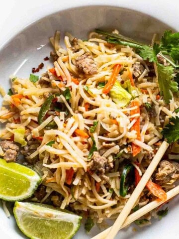 Pork pad thai noodles served on a white plate.