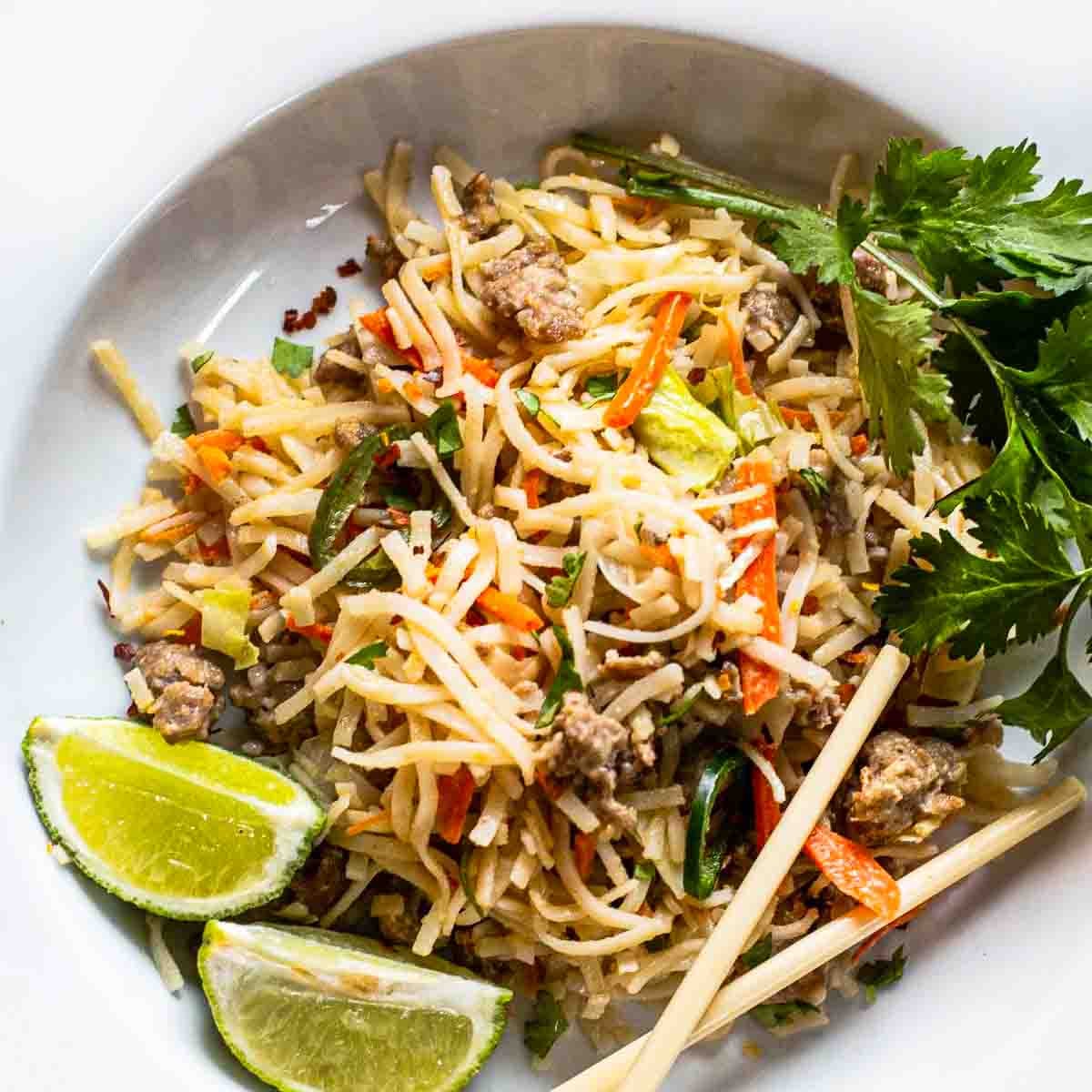 Pork pad thai noodles served on a white plate.
