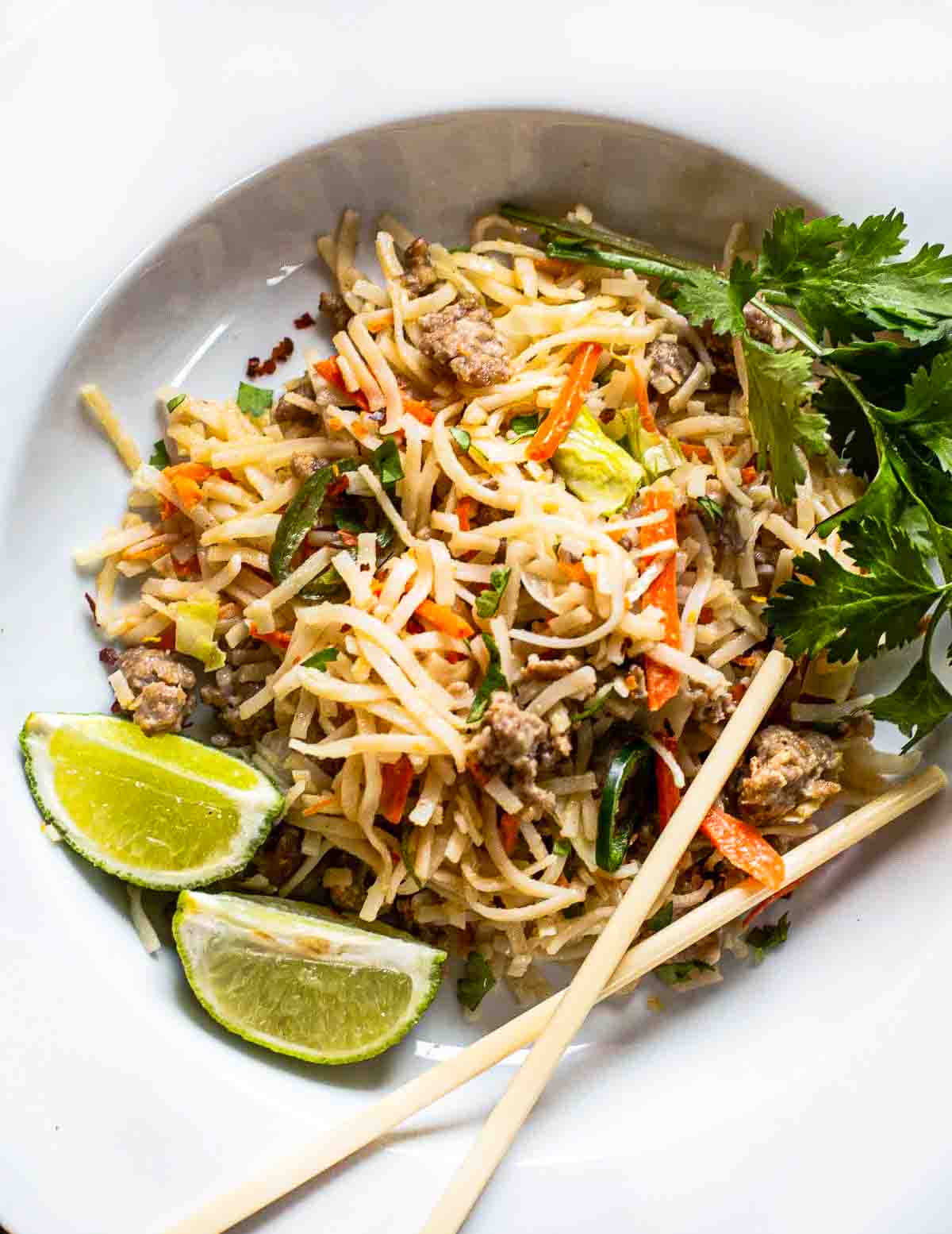 Pork pad thai noodles with peanut sauce served in a white bowl.