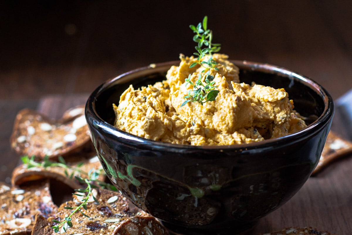 Goat cheese appetizer with pumpkin served with raincoast crisps and garnished with thyme.