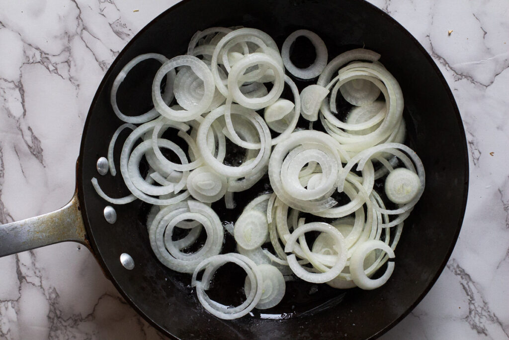 sliced onions in a fry pan read to caramelize