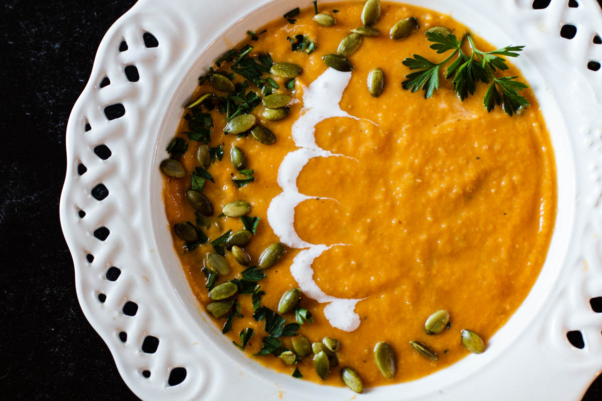 Spicy Sweet Potato Soup garnished with sour cream and pepita seeds.
