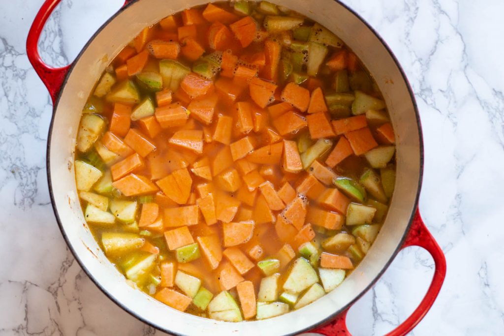 Adding sweet potatoes to broth to make sweet potato soup