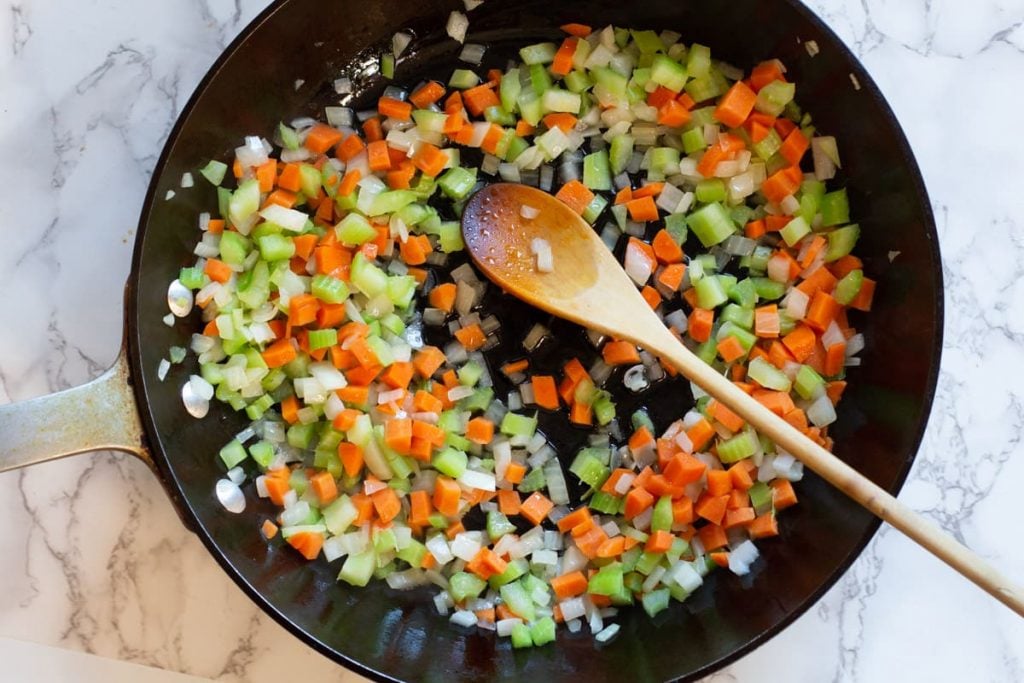 cooking chopped carrots, celery and onions to make slow cooker ham and beans