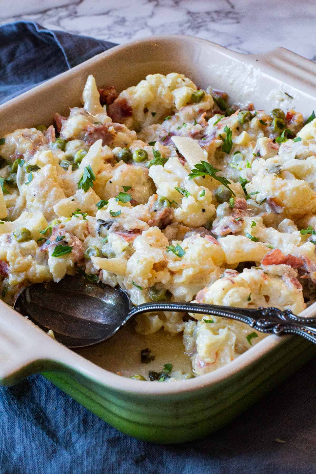 creamed cauliflower casserole with swiss cheese served in a le creuset baking dish