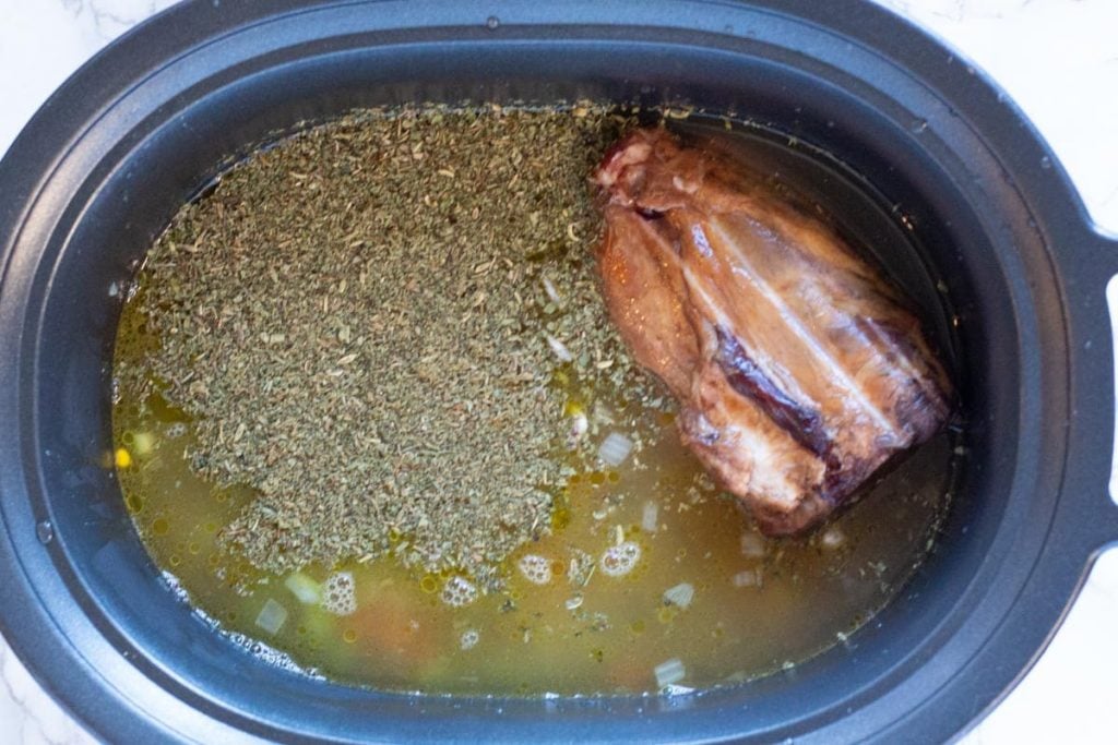 Adding chicken broth to ingredients to make crockpot ham and beans