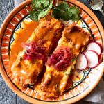 2 Pork pibel enchiladas on a festive mexican plate