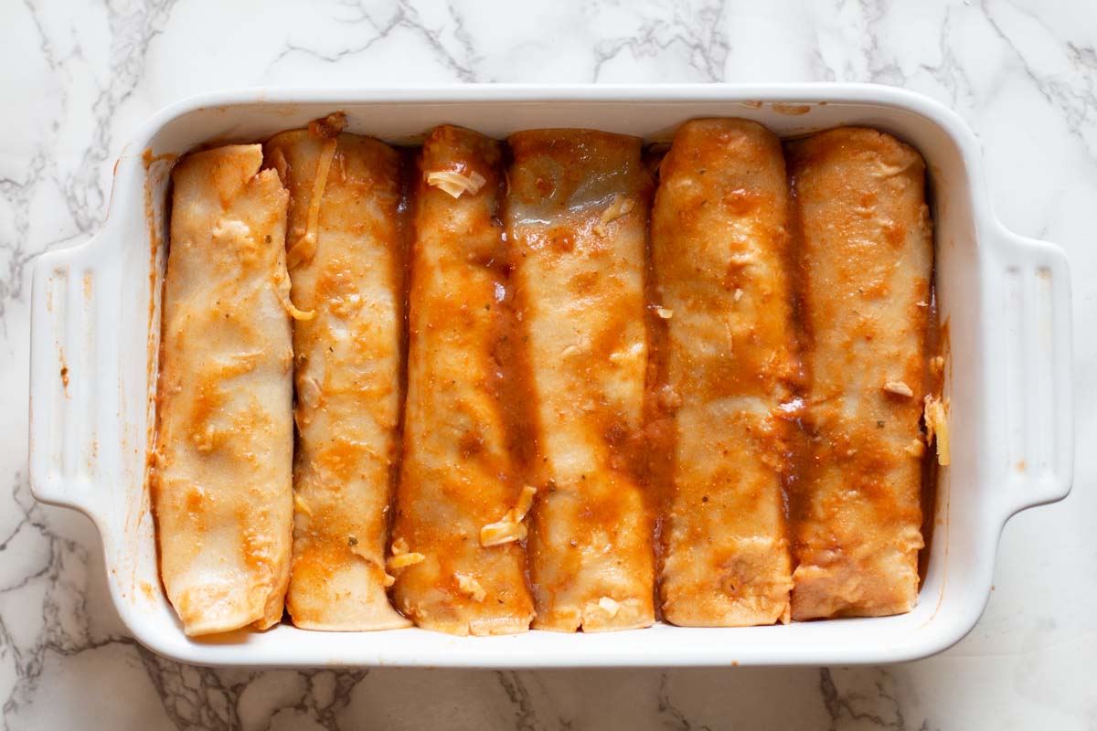 Rolled corn tortillas in a casserole dish.
