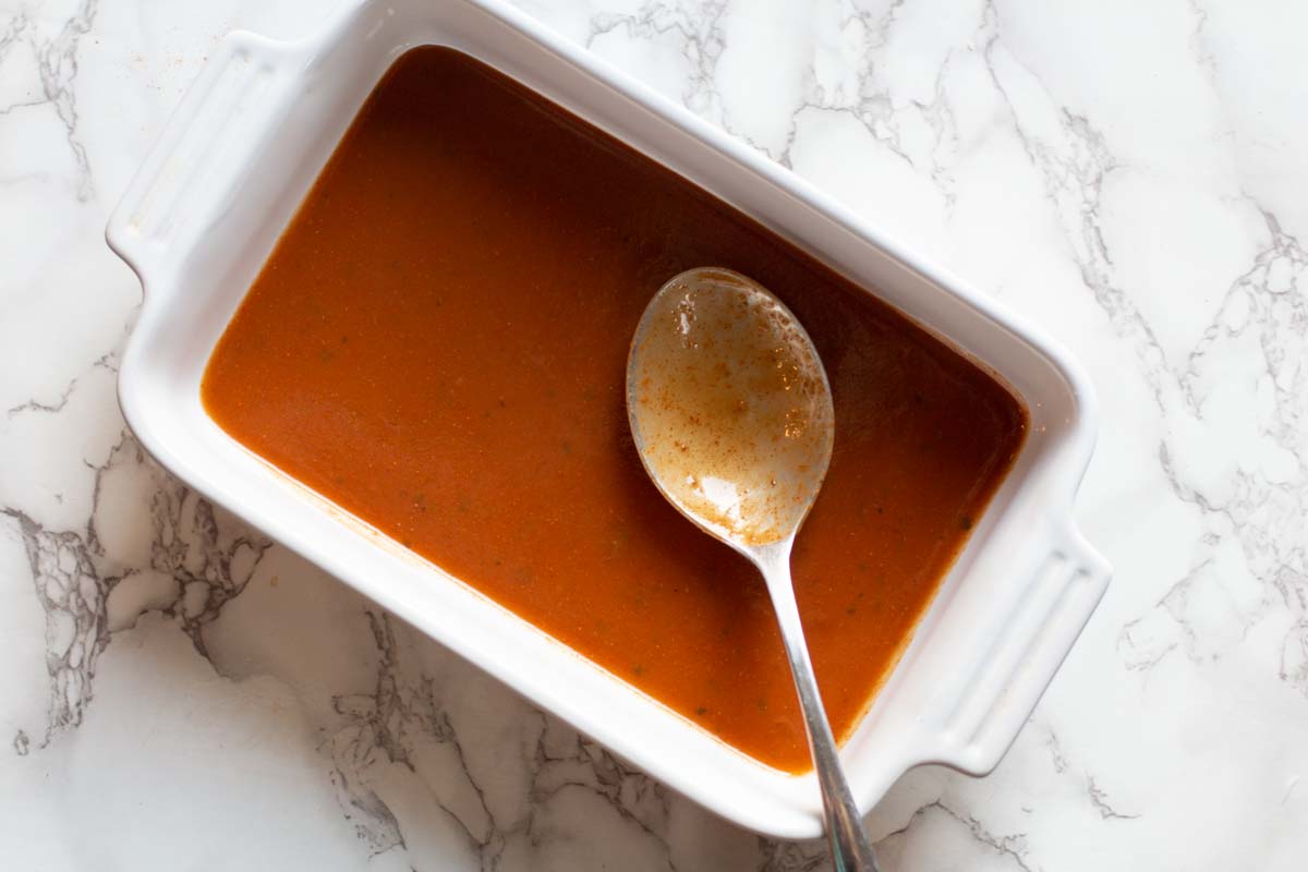 Enchilada Sauce lining casserole dish to place rolled enchiladas