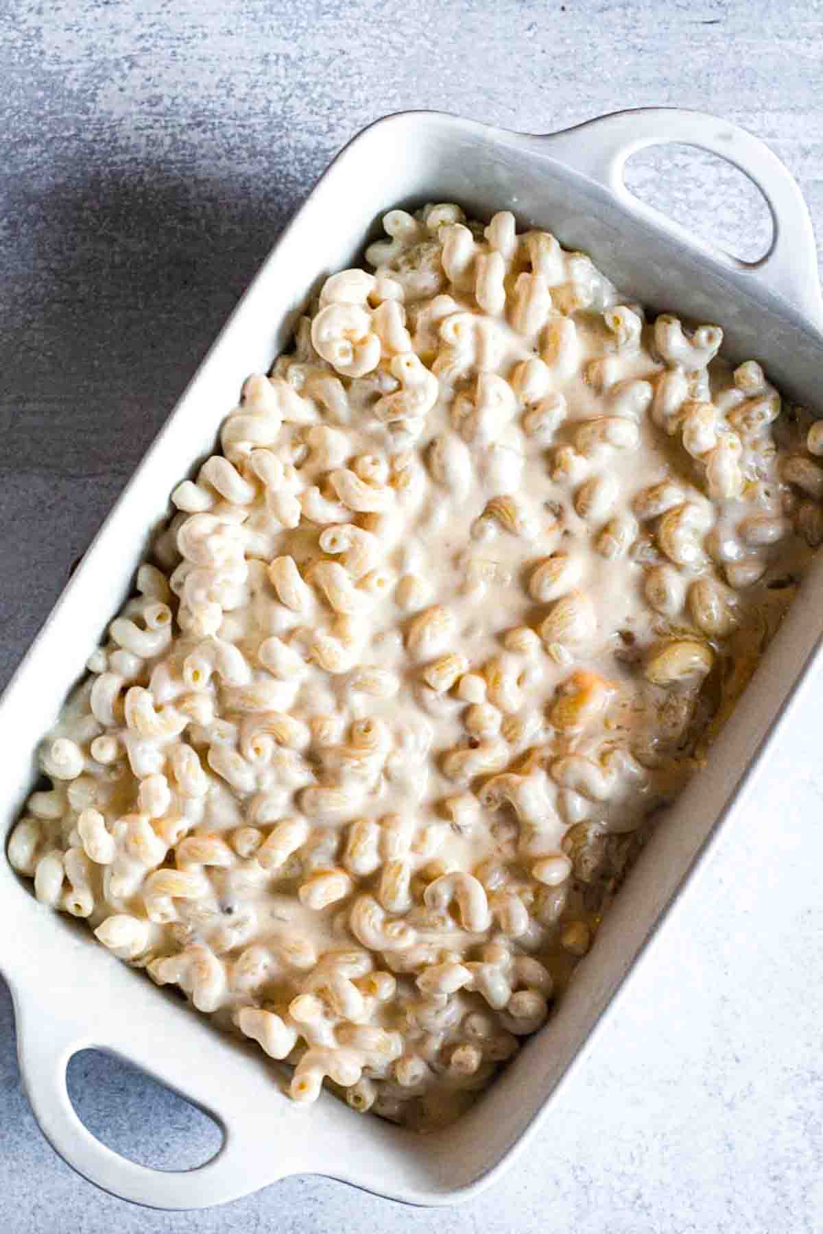 Adding mac and cheese mixture to casserole dish to bake.