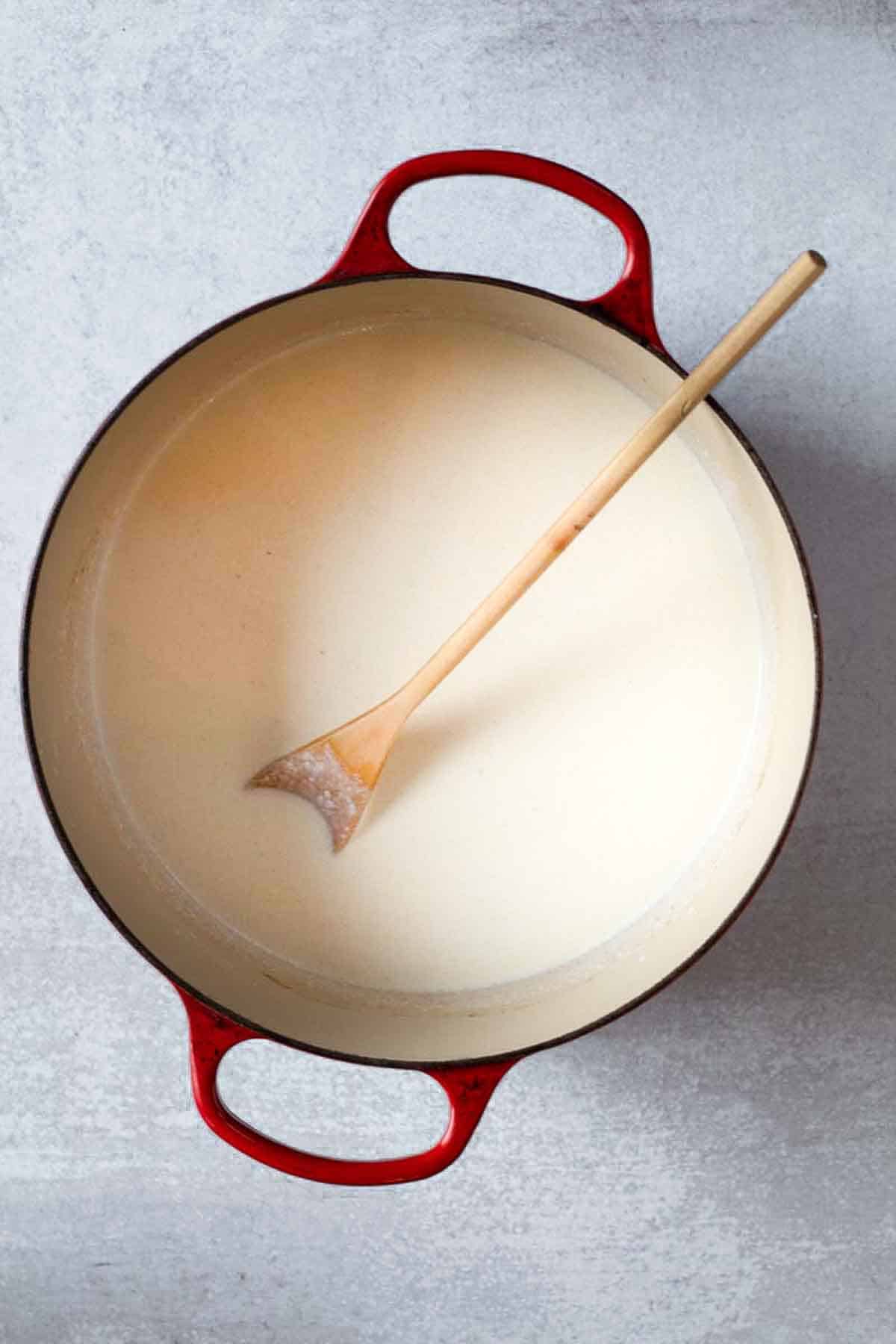 Adding milk to flour to make a roux for steakhouse mac and cheese.