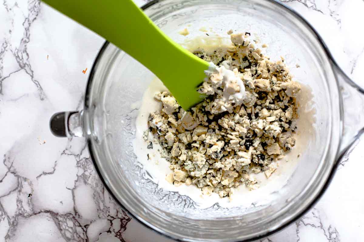 Adding chunked blue cheese to make homemade blue cheese dressing recipe.