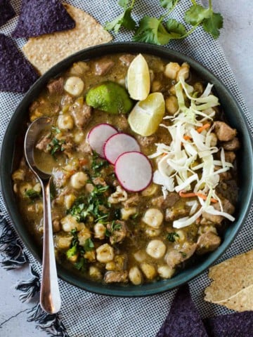 Pork pozole verde topped with sliced radish, limes and cabbage.