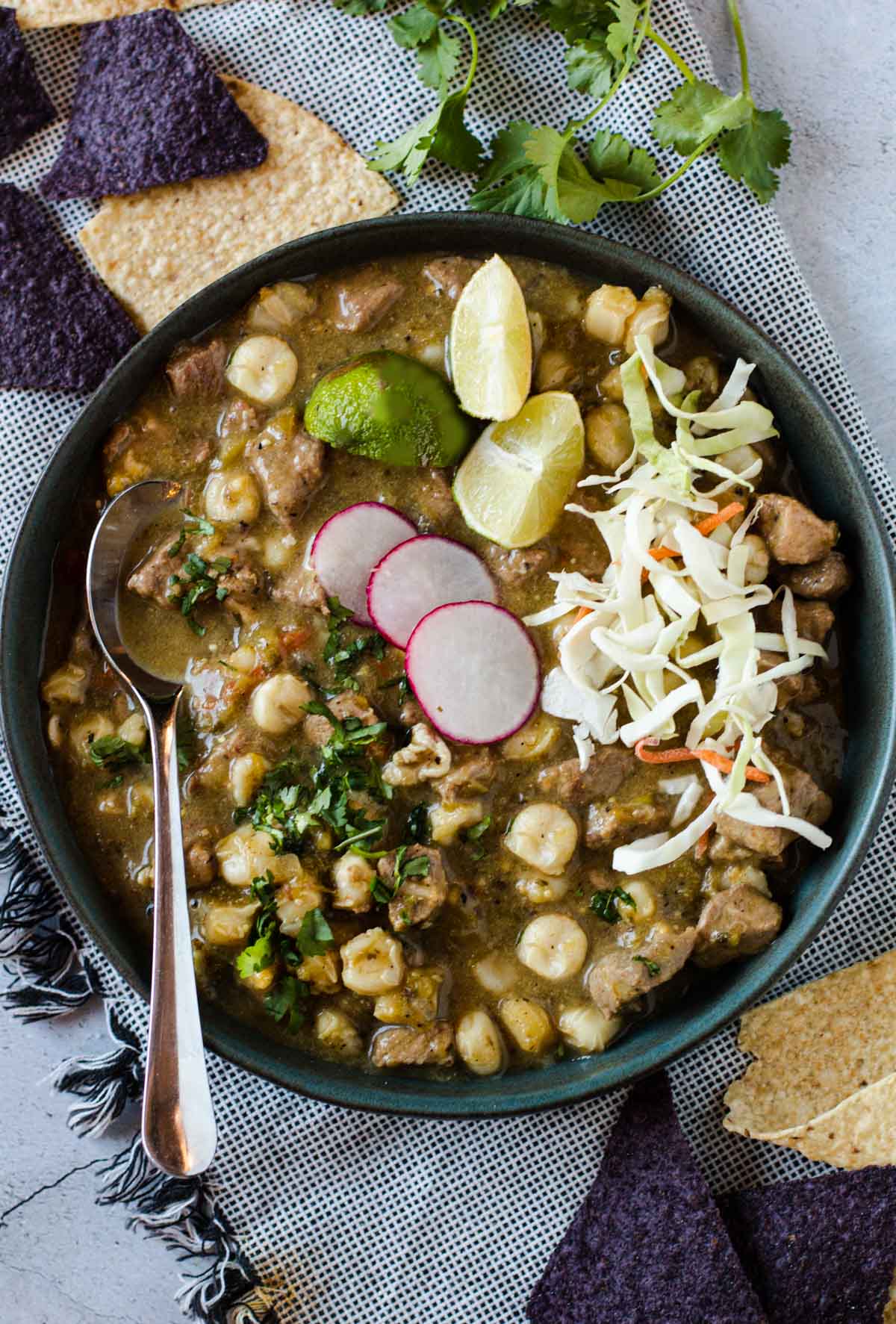 Pork pozole verde topped with sliced radish, limes and cabbage.