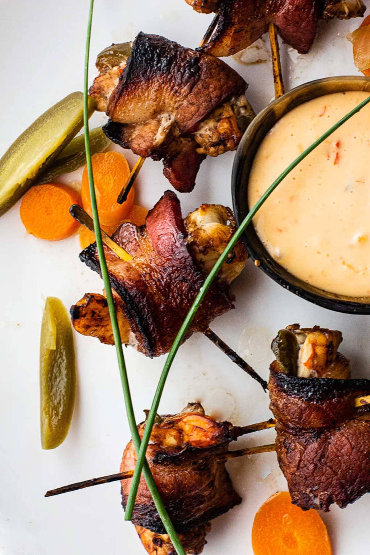 Shrimp stuffed with pickled jalapenos and wrapped in bacon served with a mayo chile sauce and garnished with pickled mexican vegetables