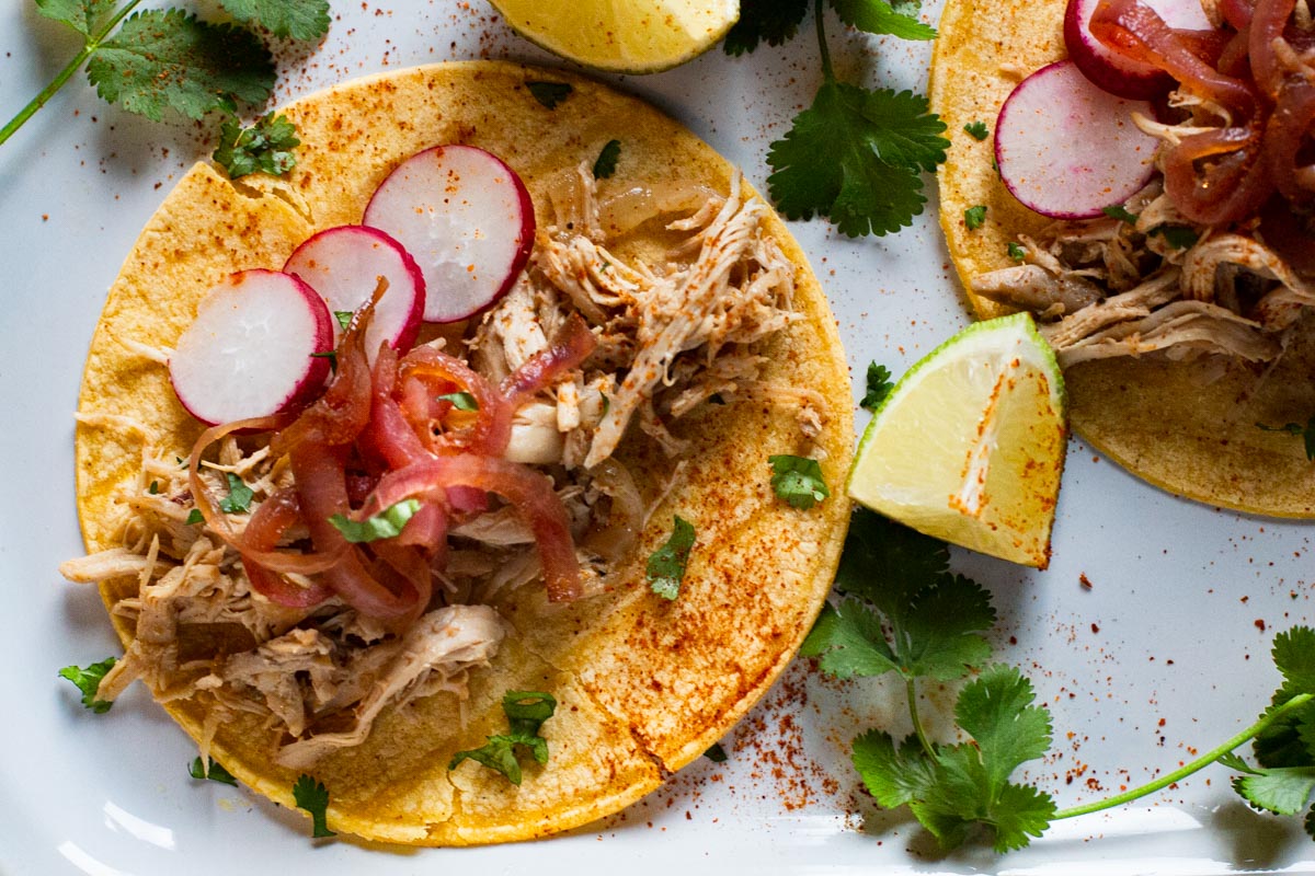 A recipe for Mexican barbacoa tacos using chicken topped with pickled onions and slices of radishes