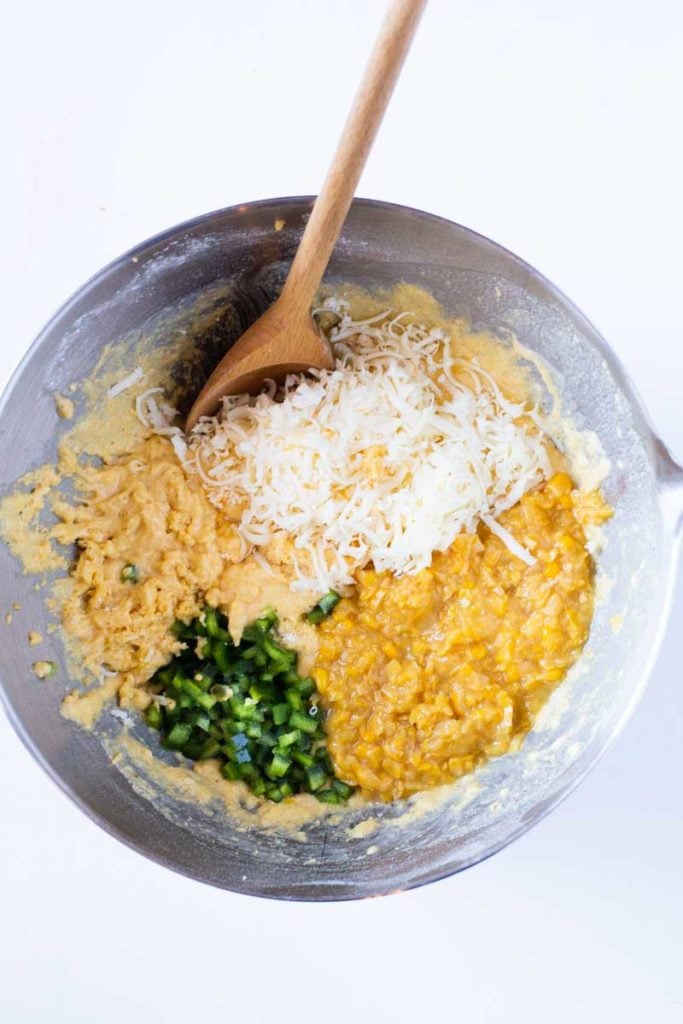 mixing creamed corn, peppers and cheese into cheesy cornbread