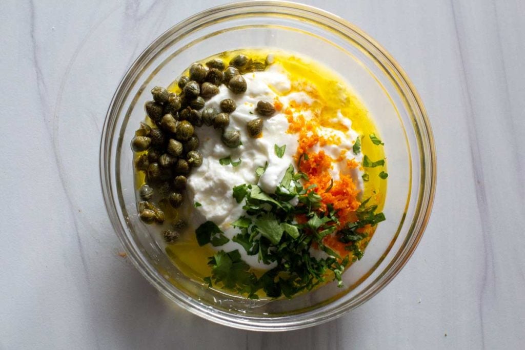 Ingredients to make yogurt caper sauce with capers, orange zest, orange juice and greek yogurt