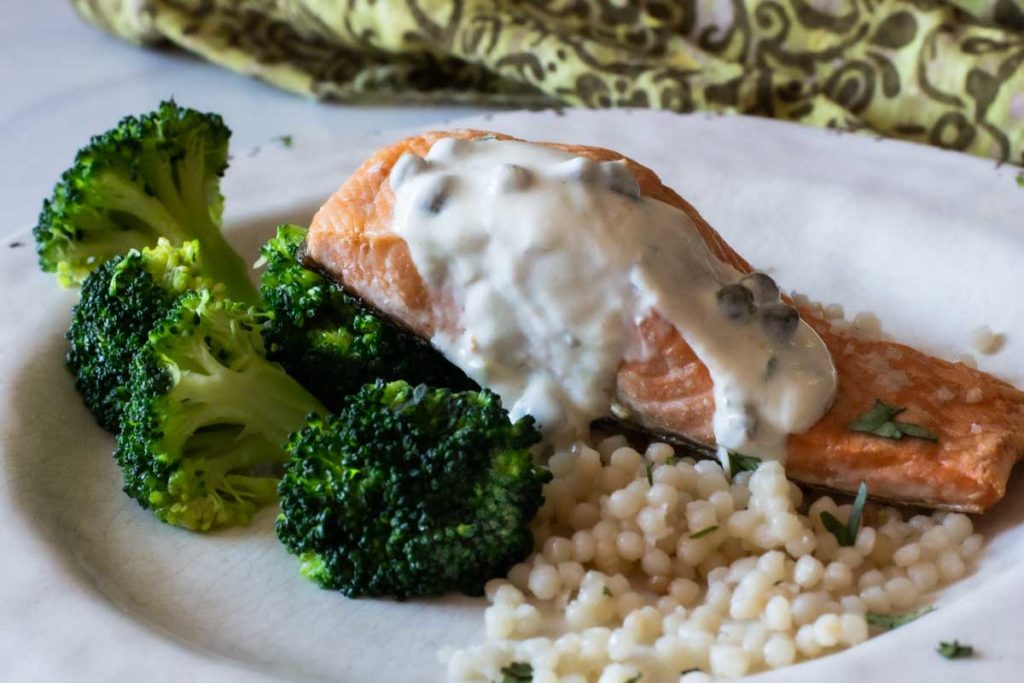 Roasted salmon topped with greek yogurt sauce served with broccoli and pearl couscous