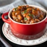 Spicy Baked Beans made from canned beans in a red casserole dish.