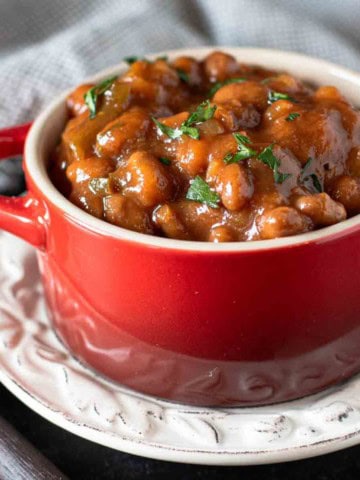 Spicy Baked Beans made from canned beans in a red casserole dish.