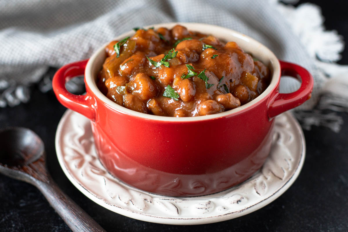 Spicy baked beans served in a red Le Creuset crock.