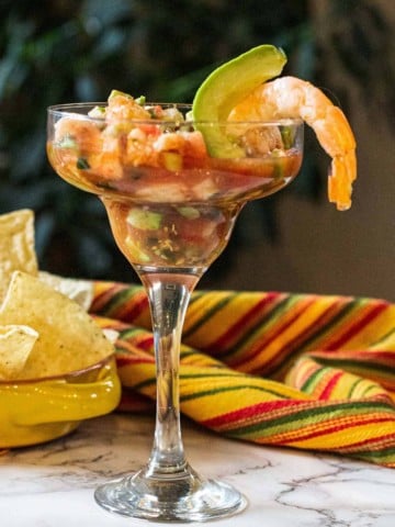 Campechana Mexican Shrimp Cocktail served in a margarita glass and garnished with shrimp and avocado. Served with corn chips