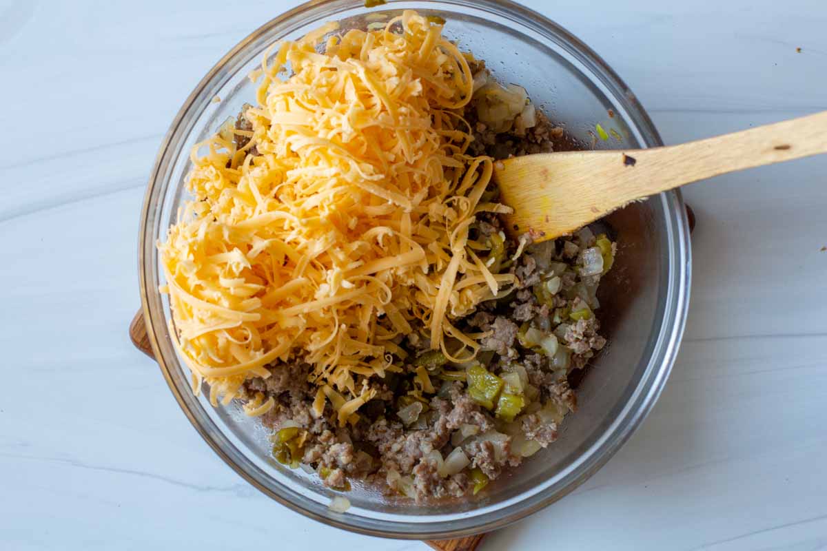 Adding shredded cheese to Jimmy Dean Sausage to make breakfast burritos
