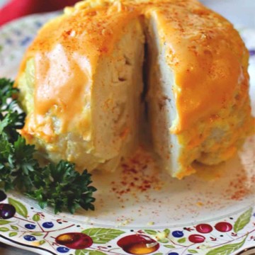 A whole head of cauliflower cooked in the microwave topped with a cheese and mayonnaise sauce