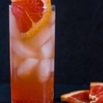 Paloma cocktail in a collins glass with slices of fresh grapefruit