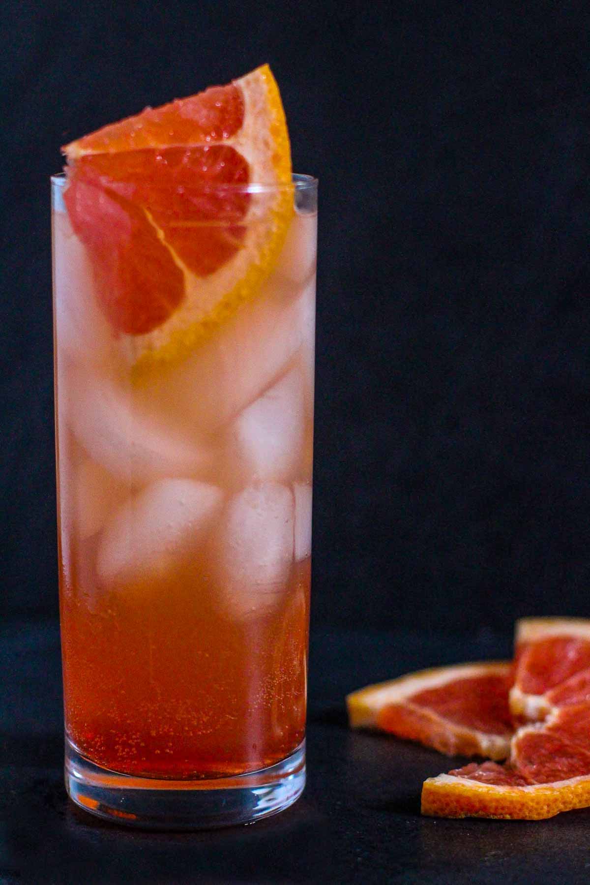 Paloma cocktail in a collins glass with slices of fresh grapefruit