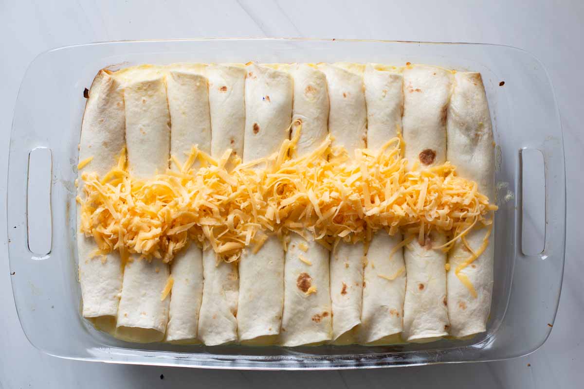 Overnight make ahead breakfast burrito casserole sprinkled with cheddar cheese