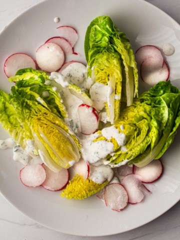 Homemade buttermilk ranch dressing on little gem salad with radishes