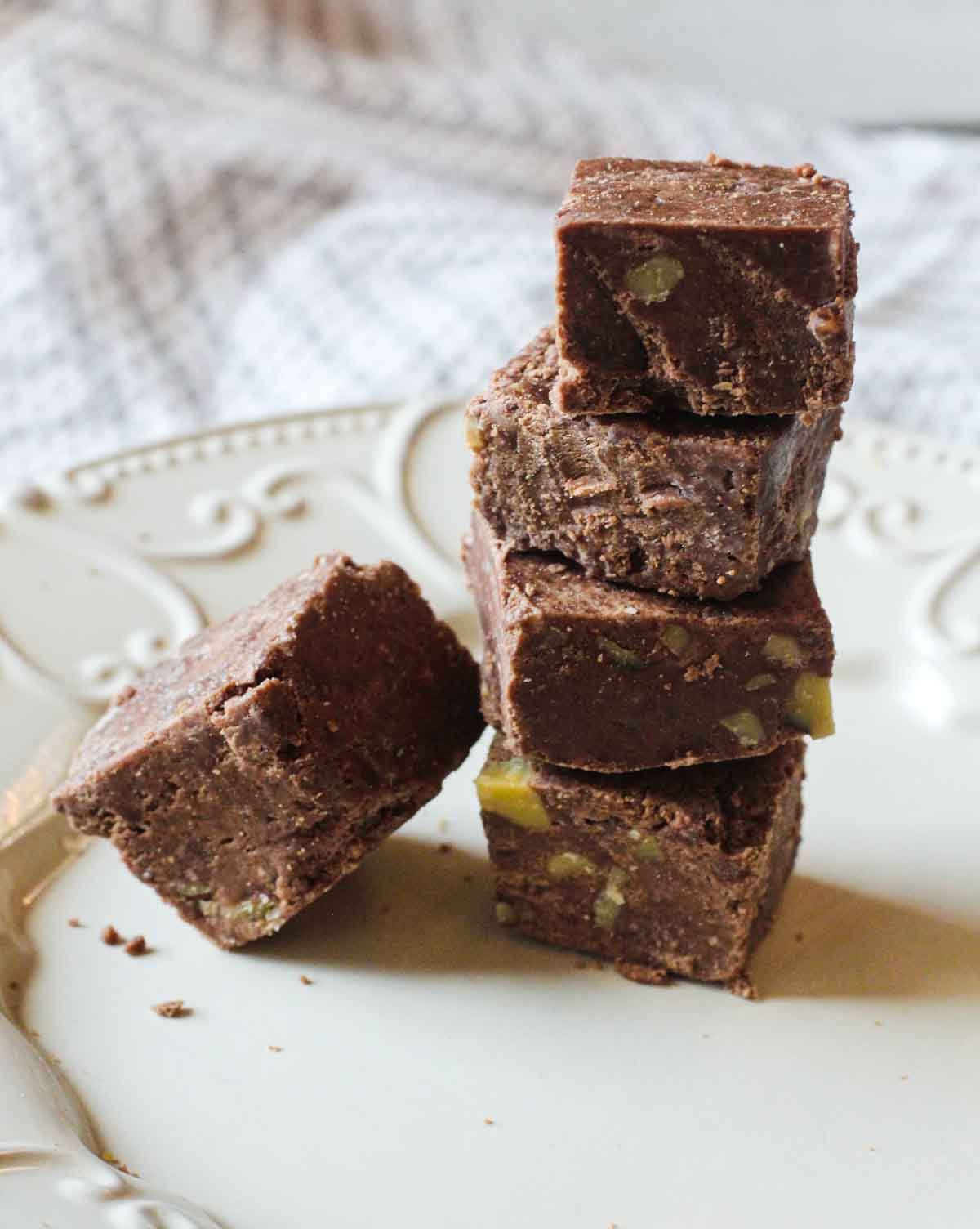 Squares of homemade fudge stacked on a plate for an award winning fudge recipe.