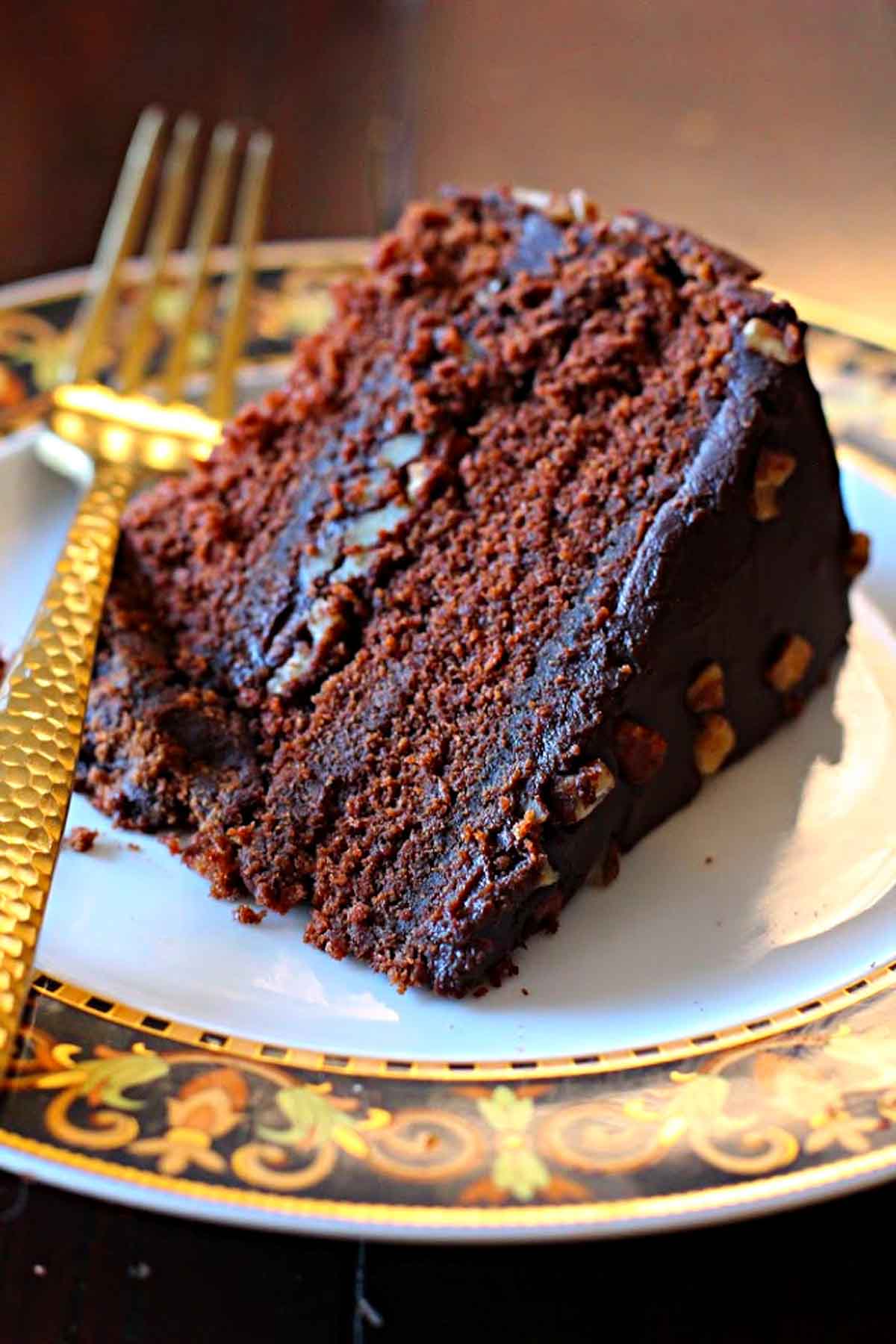 A slice of Chile chocolate cake with bourbon chocolate cake served on a Versace dessert plate with a gold flat ware fork