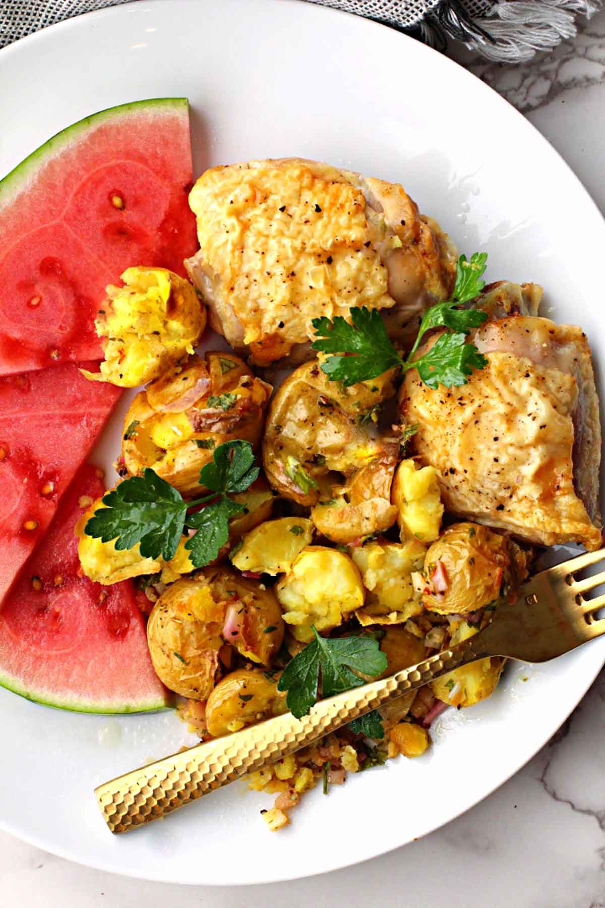 lemon baked chicken thighs served with smashed potatoes and sliced watermelon