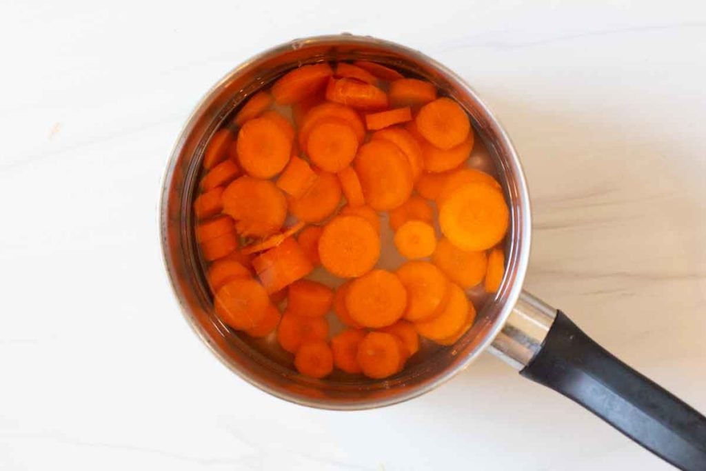blanching sliced carrots in a sauce pan