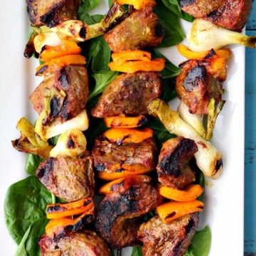 Beef kabobs on a bed of fresh spinach.
