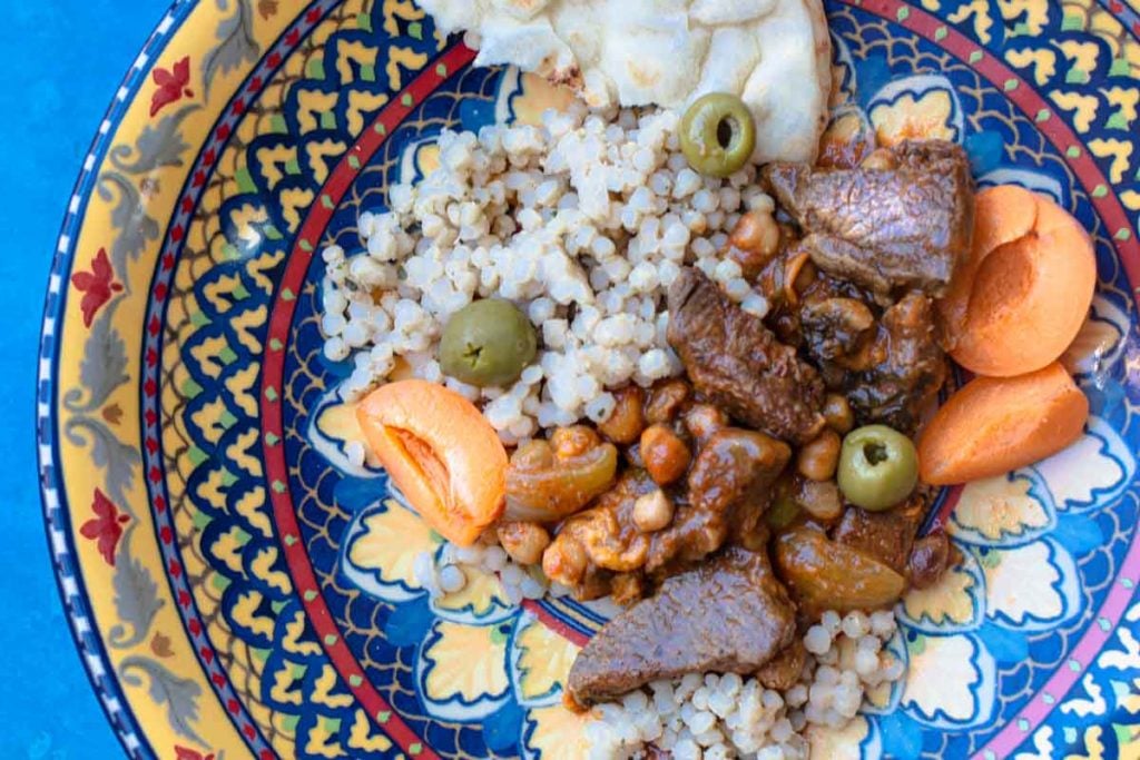 lamb tagine with apricots, chickpeas, and olives served over pearl couscous