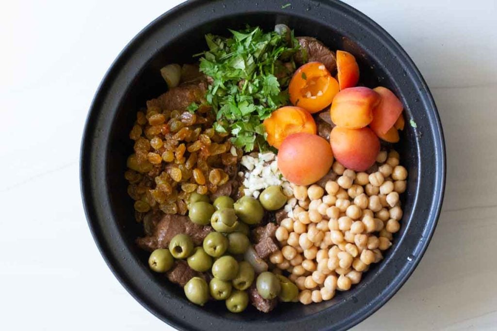 Adding ingredients to tagine pot to make apricot lamb tagine
