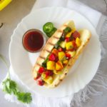 Hawaiian hot dog topped with mango pineapple salsa, sliced jalapeno peppers and bbq sauce