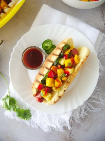 Hawaiian hot dog topped with mango pineapple salsa, sliced jalapeno peppers and bbq sauce