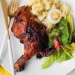 Grilled chicken halves served with potato and a salad.
