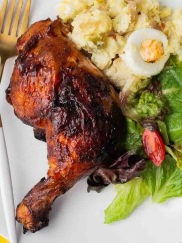 Grilled chicken halves served with potato and a salad.