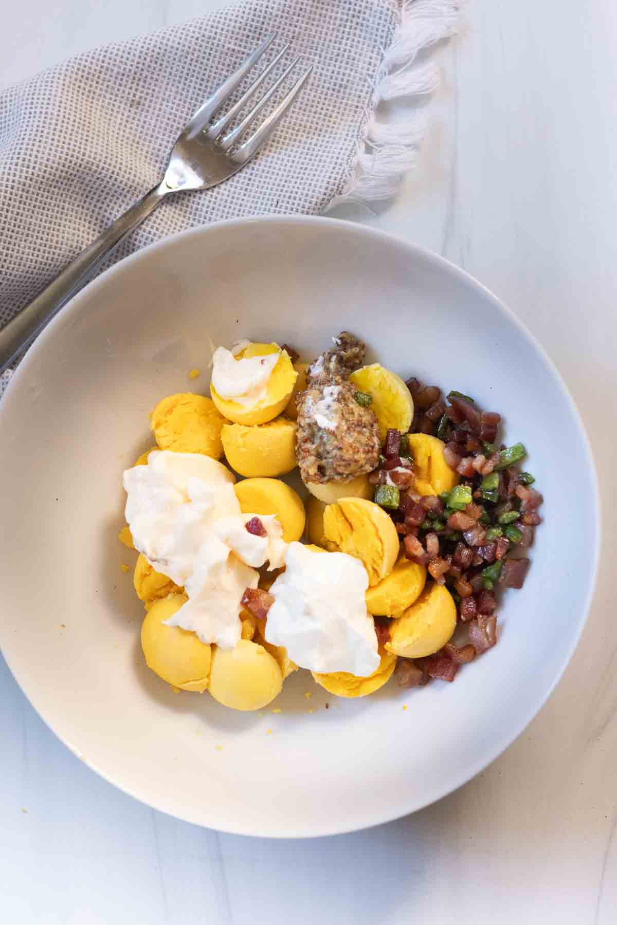 Adding ingredients in a bowl to make Bacon and Jalapeno deviled eggs.