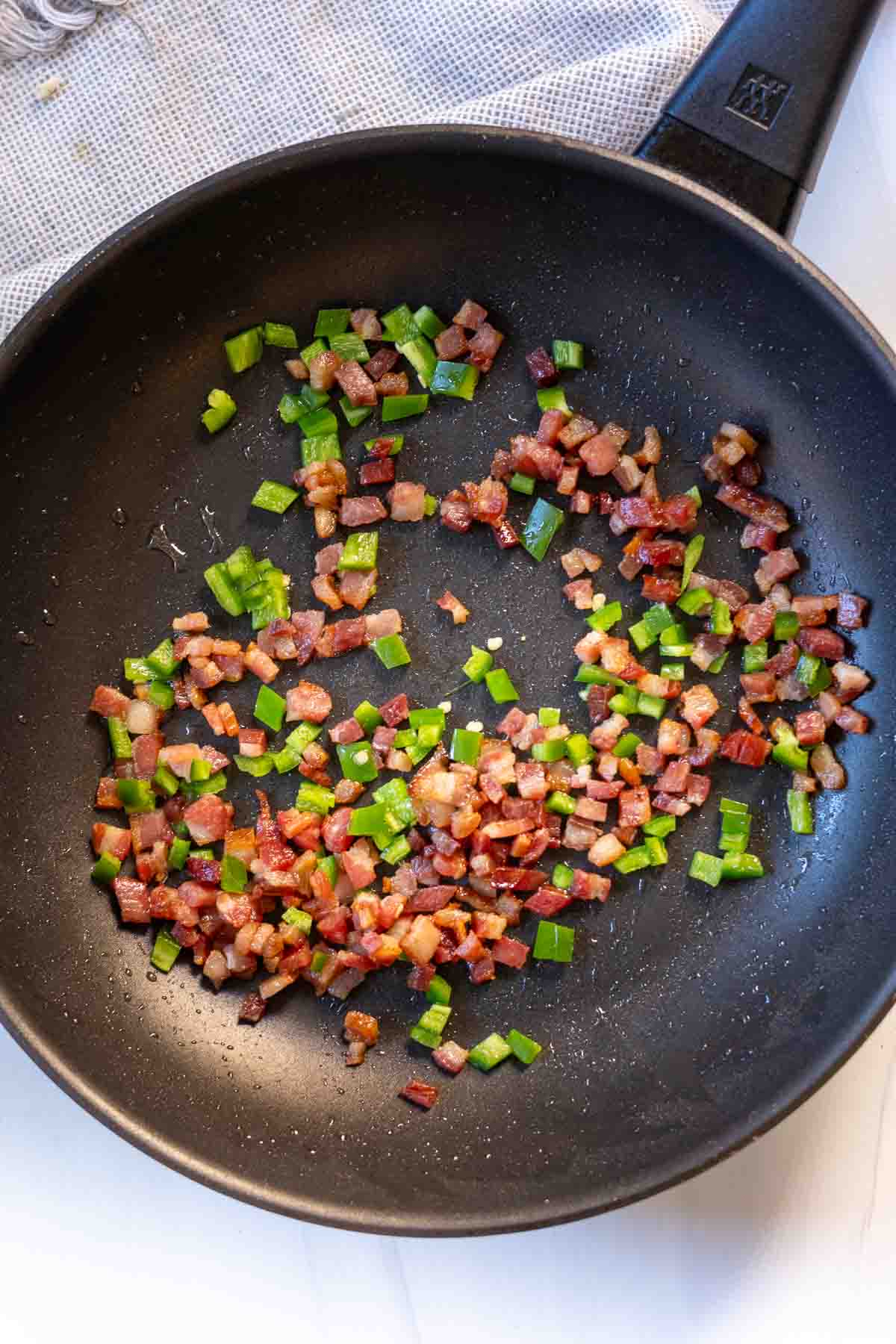 Frying chopped bacon and diced jalapeno to make bacon jalapeno deviled eggs.